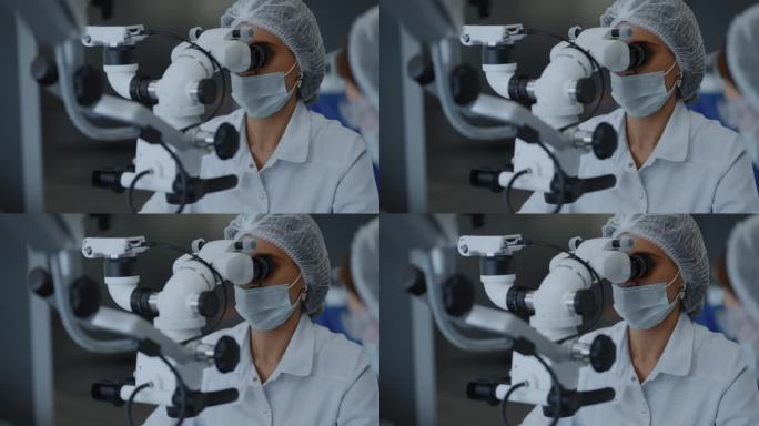 女外科医生在内窥镜手术中注视着操作显微镜
