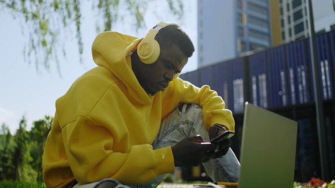 非洲裔美国学生春天在公园休息，用智能手机上网