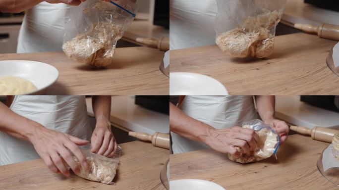 穿白围裙的女人用手把面包屑揉碎，撒在蛋糕上。