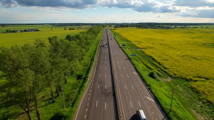 各种车辆行驶在高速公路上，周围是黄色的油菜地。