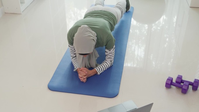 运动亚洲伊斯兰妇女穿穆斯林运动服锻炼平板支撑姿势重点核心肌肉初学者练习在线课程训练从笔记本电脑在家里