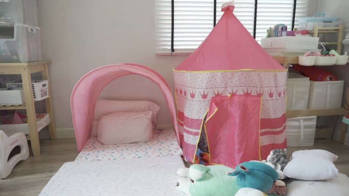 小女孩在粉红色的帐篷城堡里玩洋娃娃，在她的游戏室里有很多洋娃娃，很有趣。家装设计