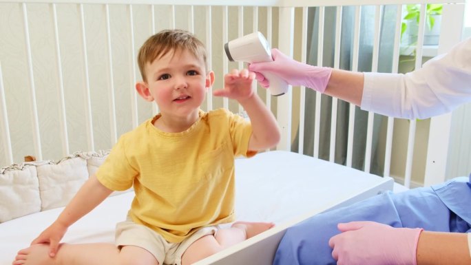 护士正在家里用一个非接触式体温计检查孩子的体温。2岁左右(1岁11个月)