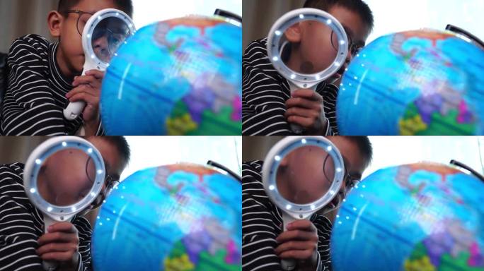 小男孩在家里用放大镜观察地球模型