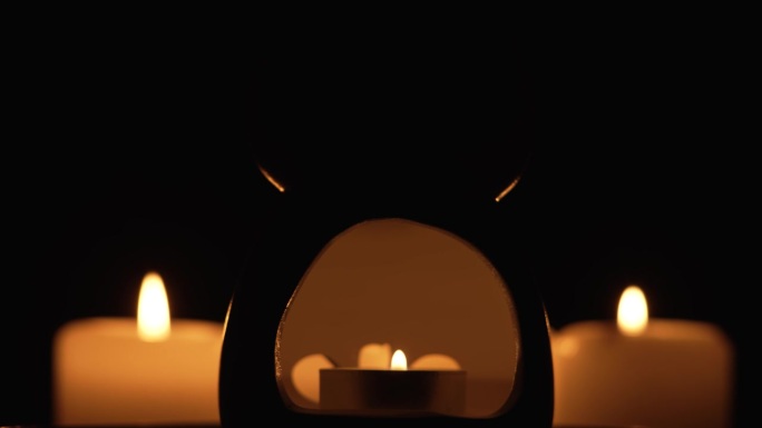万圣节旋转骷髅骷髅头在黑暗中发光。黑暗中拿着蜡烛的可怕怪物
