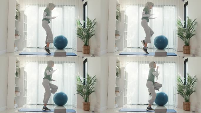 运动亚洲伊斯兰妇女穿穆斯林运动服锻炼全身锻炼高膝初学者练习在线课程训练从笔记本电脑在家里的客厅。保健