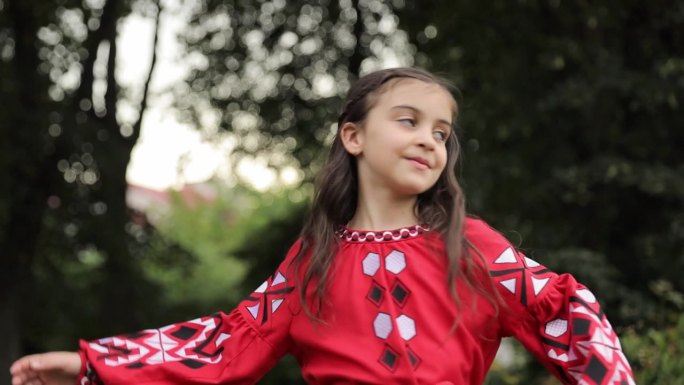 一个漂亮的小女孩穿着刺绣的衣服在森林里走着。乌克兰的刺绣。