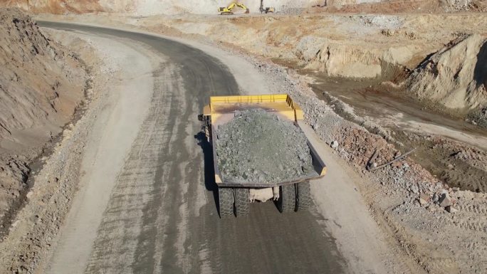 大型采石场自卸车在露天矿山运输矿石，航拍慢镜头