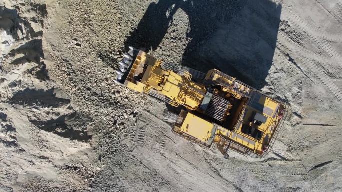 工作中的液压挖掘机在露天矿山挖矿，空中慢动作拍摄