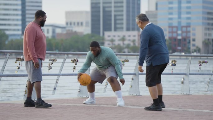 三个壮汉在城市滨水区打篮球