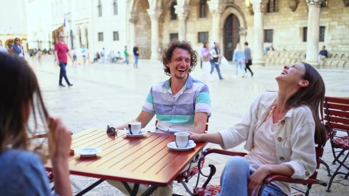 三个朋友坐在镇上的咖啡店里聊天，喝着咖啡