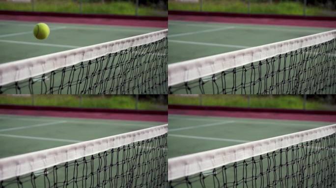 网球夹在网顶。缓慢的运动。网球打在网子上，飞到另一边去了。网球场