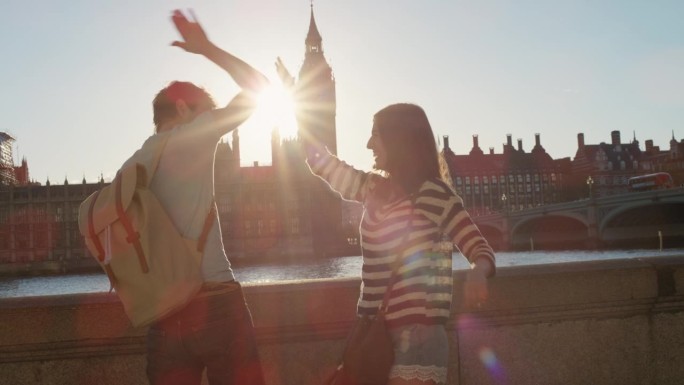 年轻的游客夫妇高举手臂，享受欧洲旅行冒险，庆祝美丽的城市观光探险