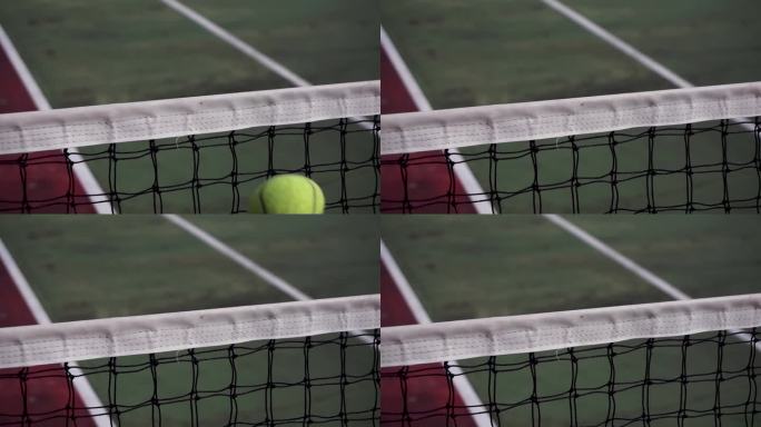 网球夹在网顶。缓慢的运动。网球打在网子上，飞到另一边去了。网球场