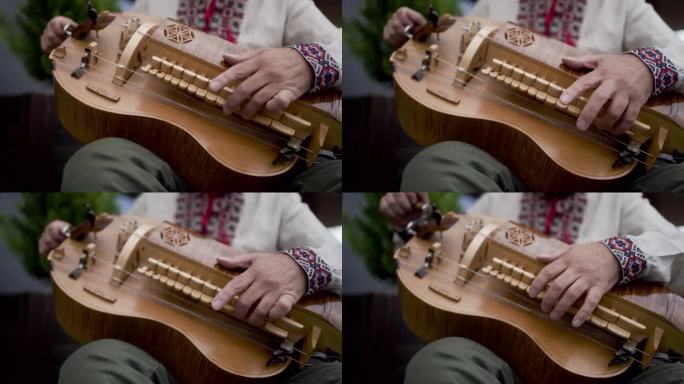 一个人正在演奏一种手摇弦乐器，这种乐器是通过一个用手摇柄转动的松香轮摩擦琴弦发出声音的。