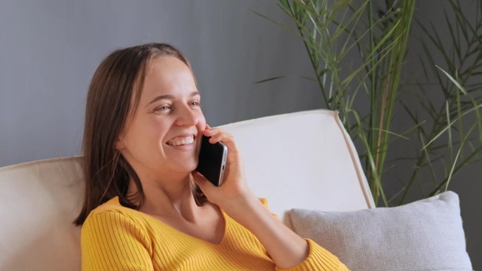 快乐美丽的白人女性参与愉快的智能手机通话与朋友分享讨论生活新闻，笑与积极的面部表情，分享八卦。