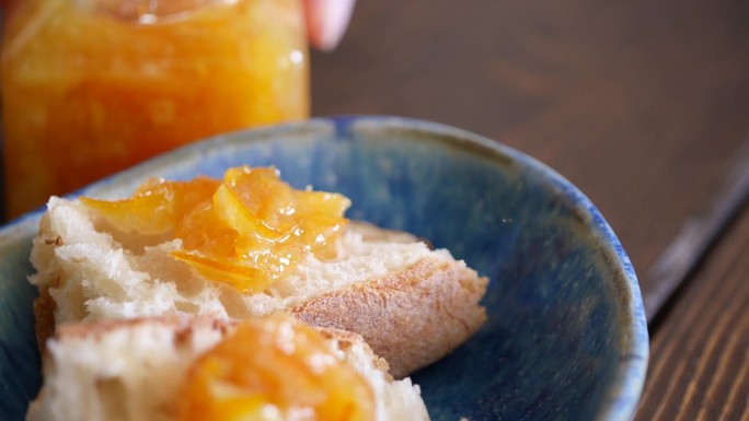 把柑橘果酱涂在法棍面包上的视频。