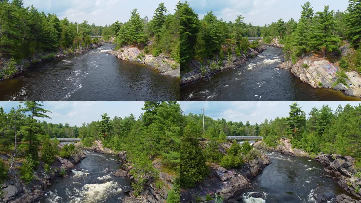 空中拍摄的湍急的河流上有岩石的页岩河岸和通向汽车桥的树木