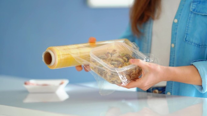 妇女用食品薄膜包装食物，以便在冰箱中储存