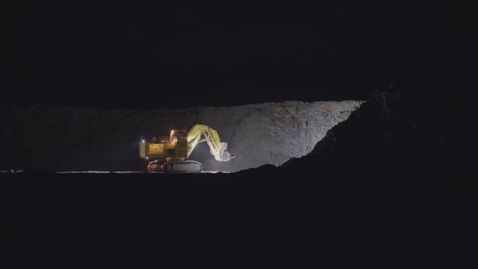 挖掘机和自卸卡车在夜间从露天矿坑中挖掘和运输金矿，慢动作