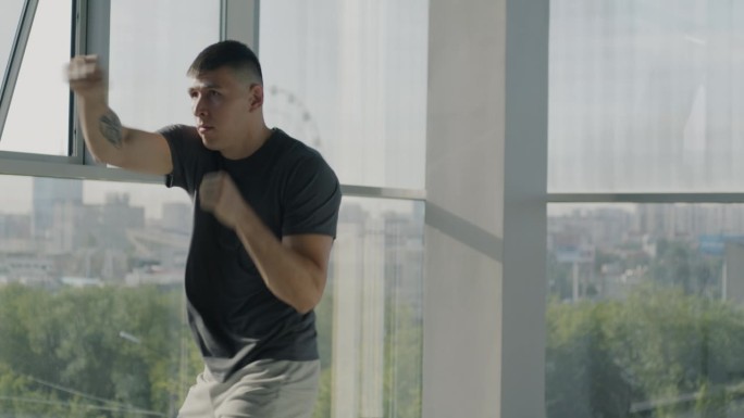 慢动作的有吸引力的年轻运动员训练手臂练习拳击动作在轻玻璃墙健身房