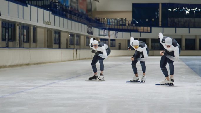 三名速滑选手在溜冰场跑道上训练