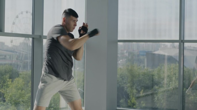 慢动作的肖像熟练的战士移动手臂包裹保护拳击影子战斗在玻璃墙健身房