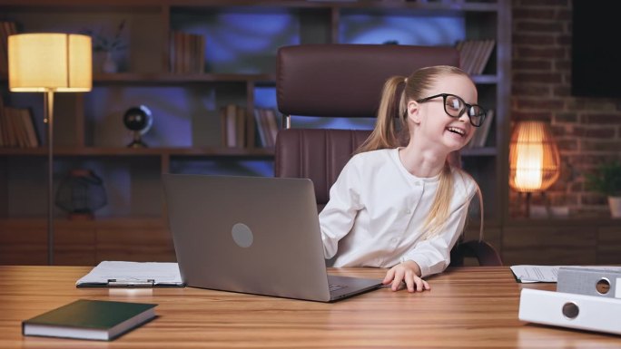 青春期前的女孩在笔记本电脑上看搞笑视频，然后大笑