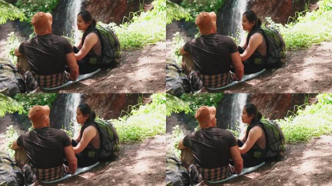 自信的跨国旅游夫妇在瀑布边聊天