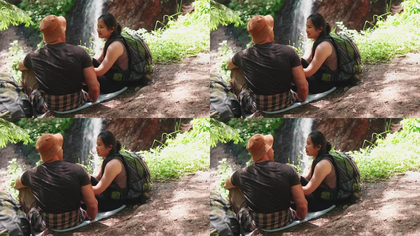 自信的跨国旅游夫妇在瀑布边聊天