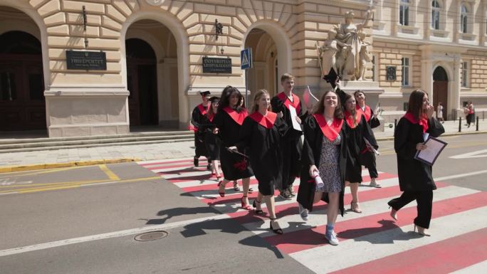 一群身着长袍的毕业生欢欢喜喜地离开大学，象征着毕业