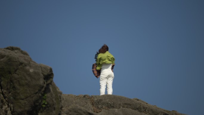 站在山顶岩石的女性背影