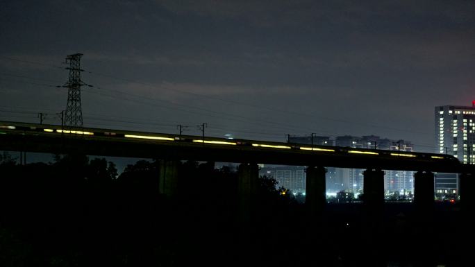 夜晚高铁动车驶过城市中的高架桥