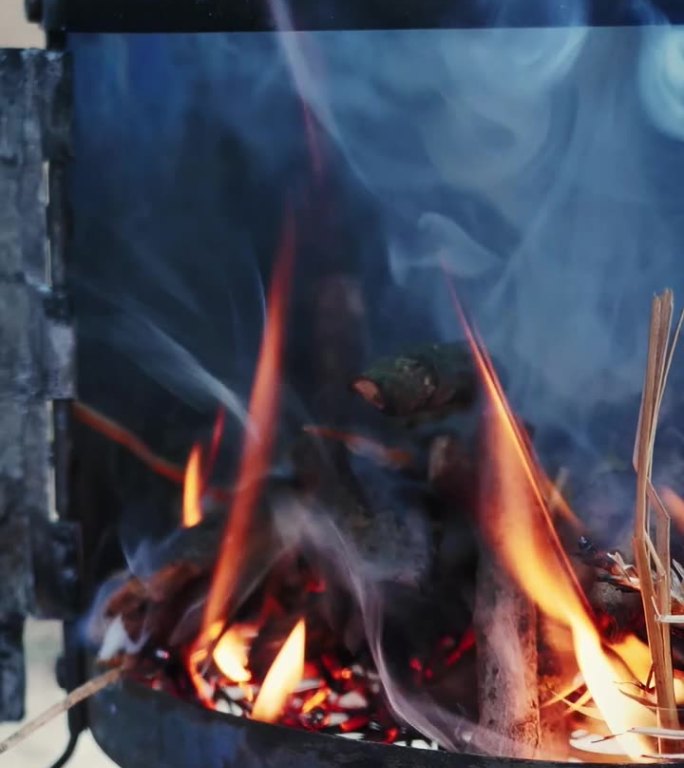 烧木头做饭用的炉子。用手把木头放进炉子。垂直视频