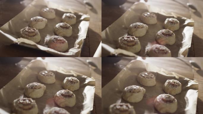 近距离拍摄的生肉桂卷糕点与糖在一个盘子里的家庭和朋友的圣诞晚餐。为节日晚上的客人准备美味的面包