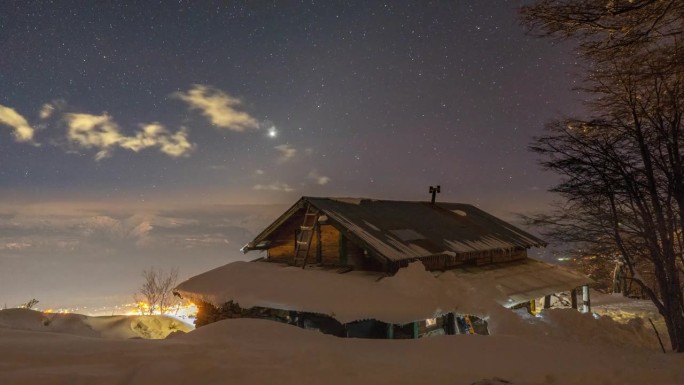 满天星斗的夜空降在高高的白净新雪的冬日小屋上方，时光流逝