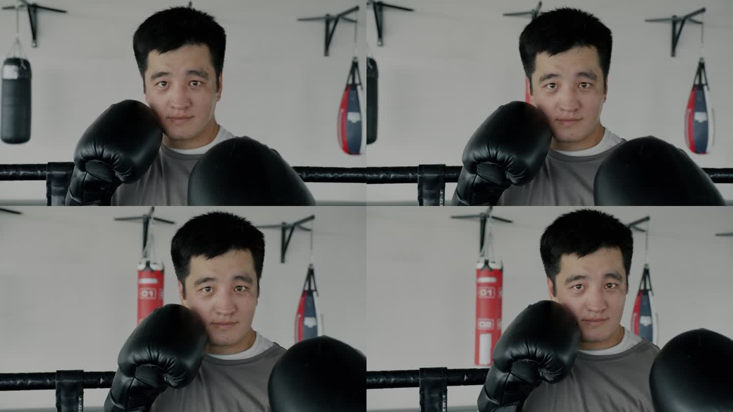 慢动作肖像的专业亚洲拳击手看着摄像机站在准备位置，戴着手套