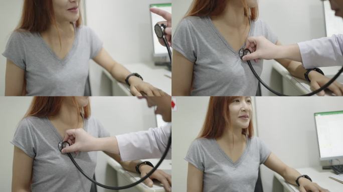 一位留着长发的亚洲女性咳嗽着，有点疼地摸着胸口，一边说话，而她的男医生正在用听诊器听她的心脏状况，以