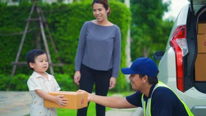 小男孩和他的妈妈从家门口好心的快递员手里接过一个包裹，心情愉快。