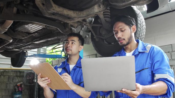 汽车修理工和团队检查汽车损坏部件的状况，在汽车修理厂诊断和修理汽车，汽车技师维修售后服务的概念。