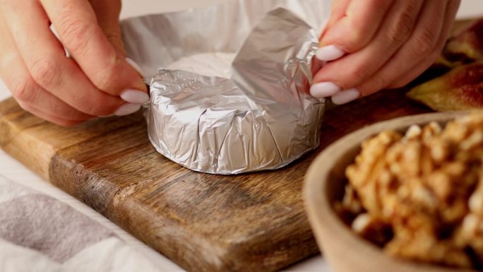 女人的手打开包在锡箔纸里的布里干酪。