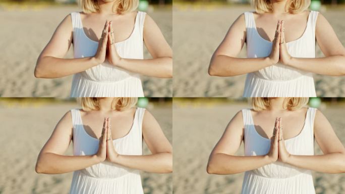 夏日日落时分，一名女子独自在沙滩上练习瑜伽，合掌感恩手印。穿白裙子的女孩。宗教，纯洁，顺从，灵性概念