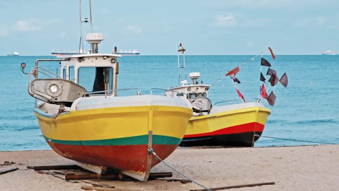 在风平浪静的日子里，一艘挂着网旗和生锈钩子的渔船停在沙滩上