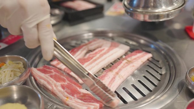 厨师在餐厅的炉子上烧烤肉和猪肉。韩式美食和传统的烧烤风格