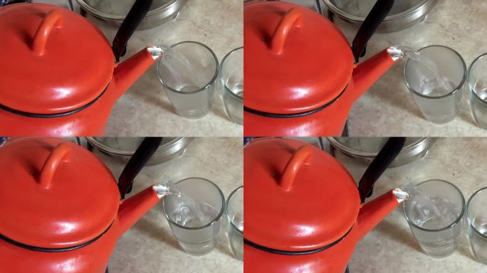 旧的红色金属茶壶。把热水倒进老式厨房的玻璃杯里