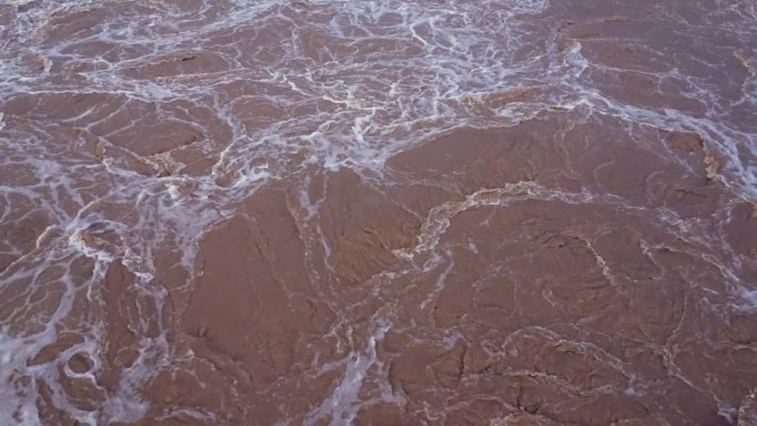 混凝土坝泄洪道泄洪鸟瞰图是雨季泄洪的一种方式。从泰国一座大坝流出的浑浊棕色森林水的俯视图。