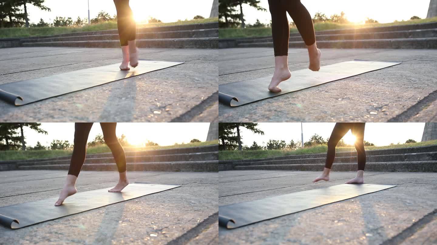 不知名的女芭蕾舞演员在公园里做热身运动。她在运动垫上踮着脚尖走路