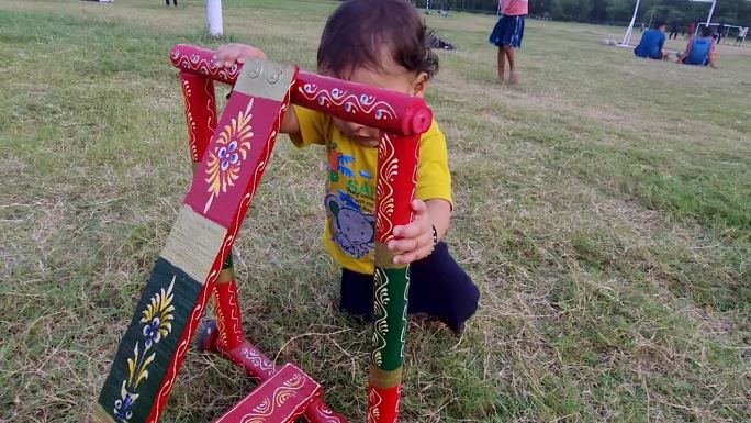 幼儿从不同的角度在户外用传统的木质学步车学习走路