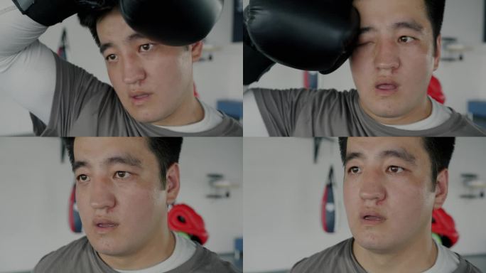 疲惫的亚洲运动员在休息时用拳击手套擦去脸上的汗水的特写