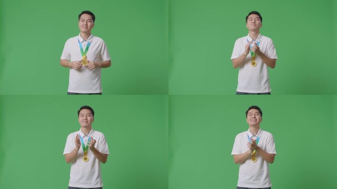 亚洲男子戴着金牌，自豪地鼓掌，成为工作室绿幕背景下的第一位获奖者